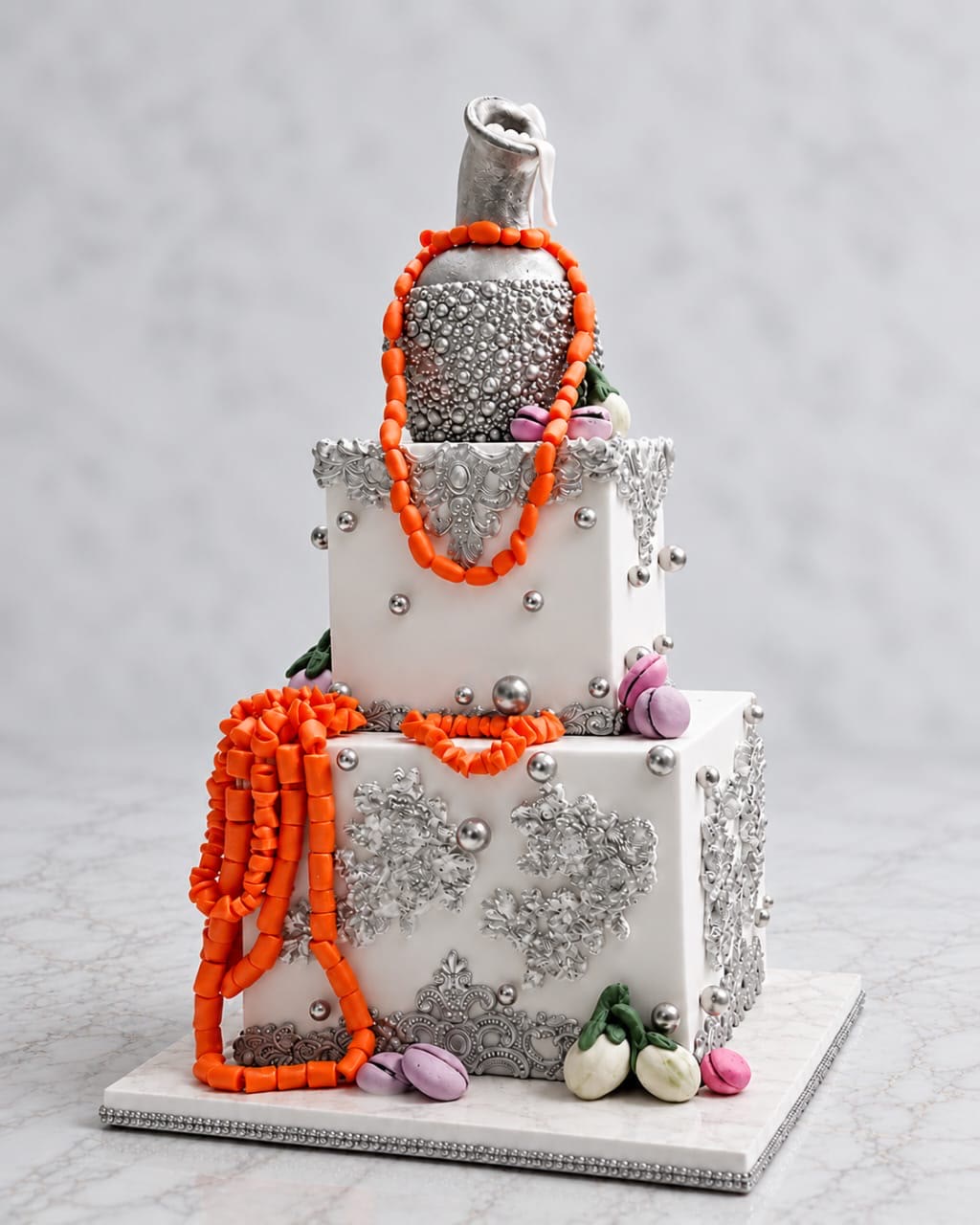 Traditional wedding cake with silver lace, coral bead strands and small calabashes