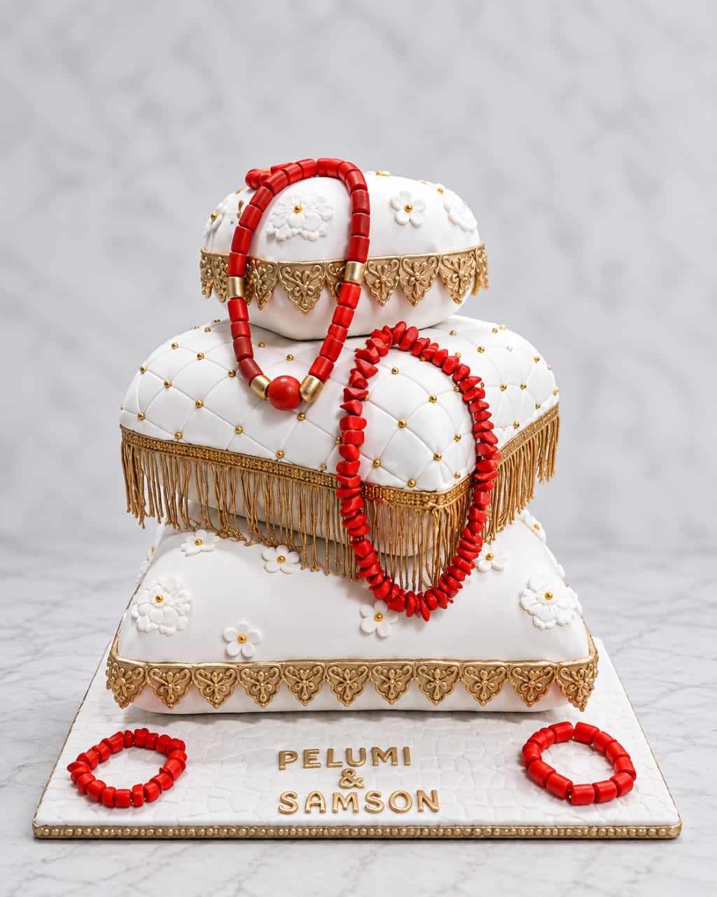 Engagement cake shaped like stacked pillows with red coral beads