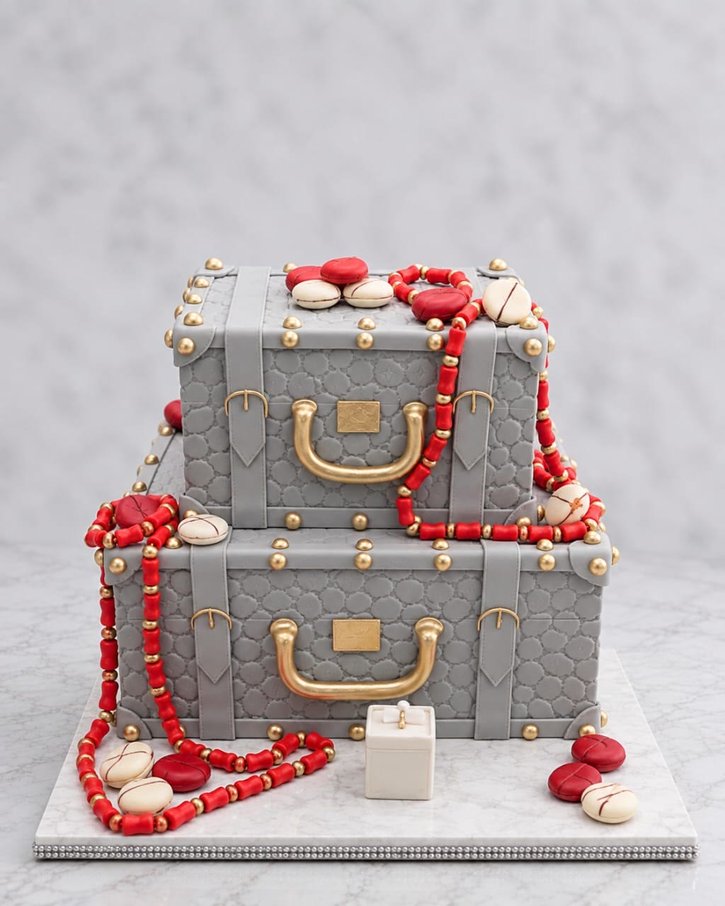 Grey suitcase wedding cake with gold handles and coral beads